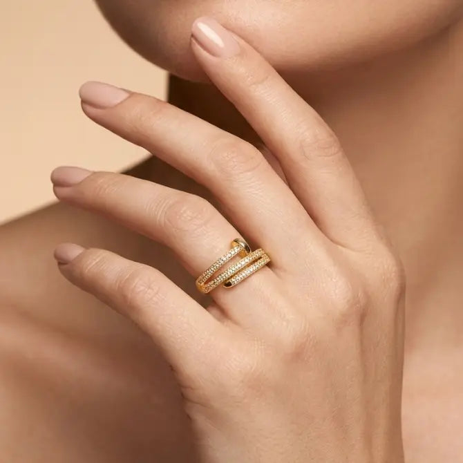Close-up of a hand wearing two gold rings on a beige background