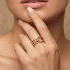 Close-up of a hand with a gold ring near the face against a neutral background