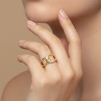 Close-up of a hand wearing two gold rings with a soft beige background