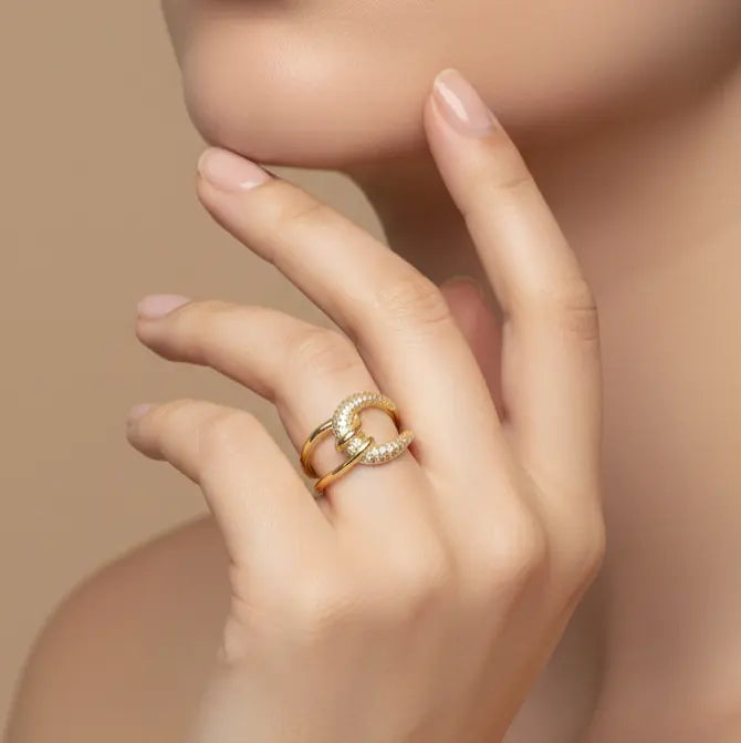 Close-up of a hand wearing two gold rings with a soft beige background