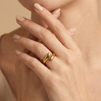 Close-up of a hand wearing a gold ring on a beige background