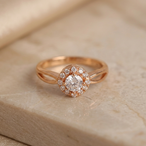 Rose gold ring with a diamond on a beige stone surface