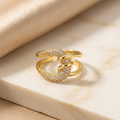 Gold snake-shaped ring with diamond accents on a beige fabric background