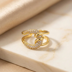 Gold snake-shaped ring with diamond accents on a beige fabric background