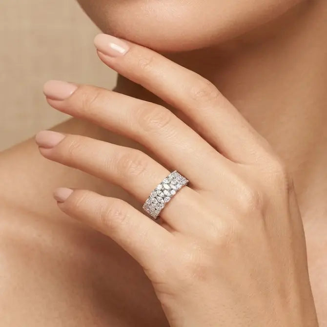 Close-up of a hand wearing a diamond ring with a neutral background